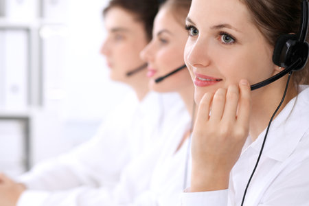 Call center. Focus on beautiful woman in headsetの写真素材