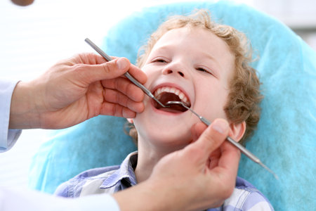 Close up of boy having his teeth examined by a dentistの写真素材