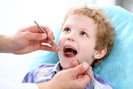 Close up of boy having his teeth examined by a dentistの写真素材