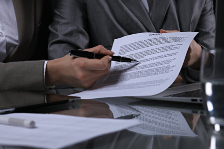 Group of business people and lawyers discussing contract sitting at the table. Woman chief is taking pen for signing papers. Low key lightingの写真素材