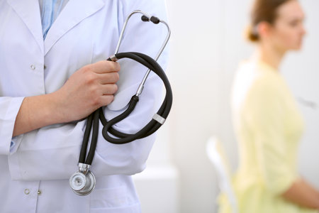 Doctor holding a stethoscope in his hands , the patient on the backgroundの写真素材