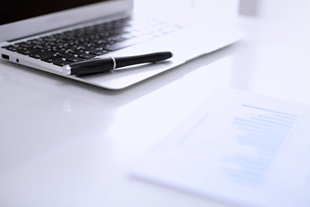 Office workplace with a laptop and financial documentsの写真素材