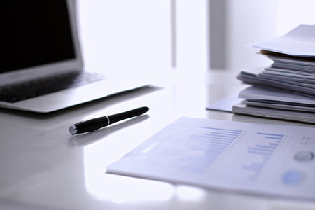 Office workplace with a laptop and financial documentsの写真素材