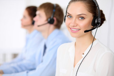Call center operators. Young beautiful business woman in headset. Male call operator in headset at the backgroundの写真素材