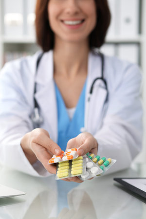 Female doctor hand holding pack of different tablet blisters closeup. Life save service, legal drug store, prescribe medicament, blood pressure, disease healing conceptの写真素材