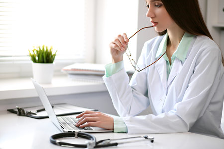 Female doctor brunette sitting  at the table near the window in hospitalの写真素材