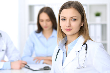 Young beautiful female doctor smiling  on the background with patient  in hospitalの写真素材
