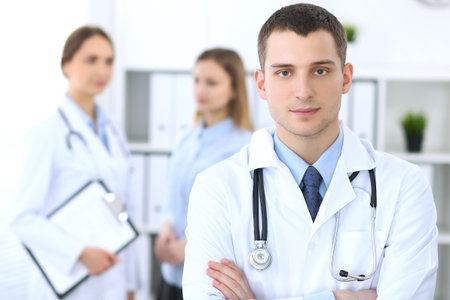 Friendly male doctor  on the background with patient  and physicianの写真素材