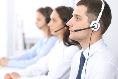 Call center operators. Focus at businessman in headset while consulting customersの写真素材