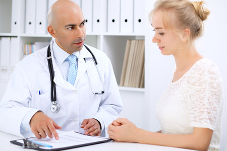 Confident bald doctor man consults his female patientの写真素材