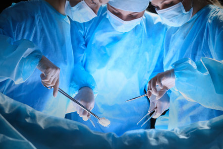 Group of surgeons at work in operating theater toned in blueの写真素材