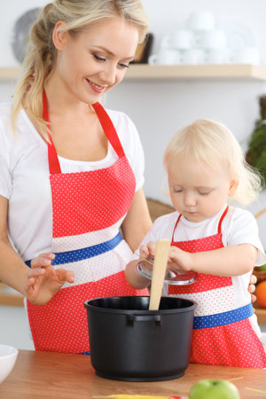 Mother and child daughter  cooking pasta or salad for the breakfast. Concept of happy family in the kitchenの写真素材