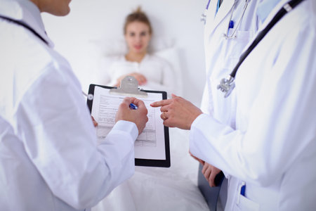 A group of doctors discussing medical history close up , a happy smiling patient in the background.