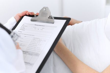 Close-up of a female doctor holding application form while consulting patient.の写真素材