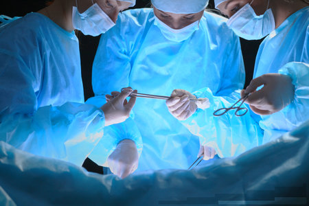 Group of surgeons at work in operating theater toned in blueの写真素材