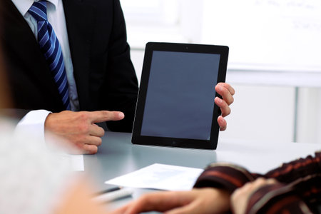 Group of business people at meeting, close up. Boss pointing into tablet computer monitor.の写真素材