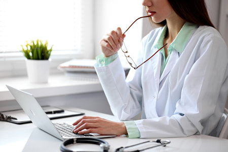 Close up of  unknown female doctor sitting  at the table near the window in hospitalの写真素材