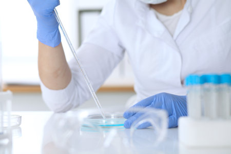 Close up of scientific research hands with clear solution in laboratory.の写真素材