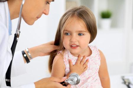 Doctor examining a little girl by stethoscopeの写真素材