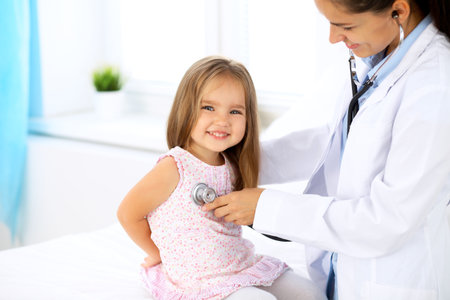 Doctor examining a little girl by stethoscopeの写真素材
