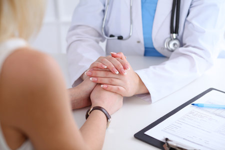 Close up of doctor hands reassuring her female patientの写真素材