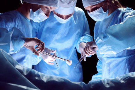 Group of surgeons at work in operating theater toned in blueの写真素材