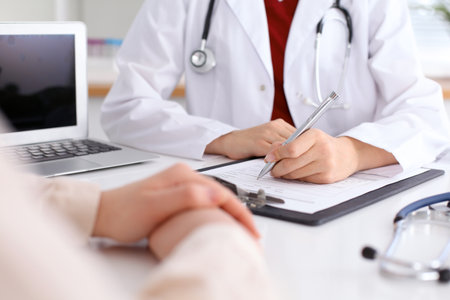 Close up of a female doctor filling up  an application form while consulting patient. Medicine and health care conceptの写真素材