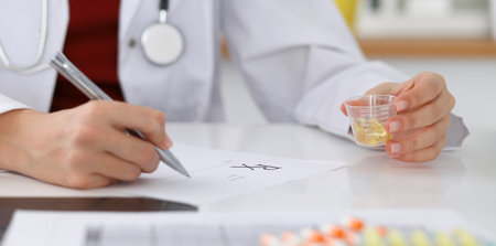 Female medicine doctor fills up prescription form to patient closeup. Panacea and life save, prescribe treatment, legal drug store, contraception concept.の写真素材