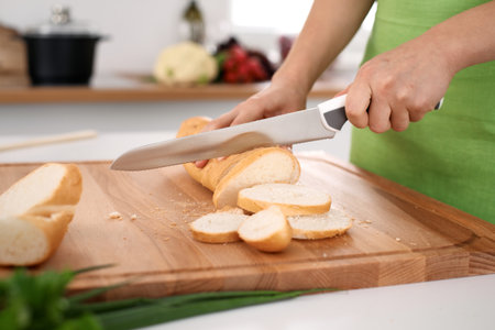 Close up of womans hands cooking in the kitchen. Housewife slicing white bread.の写真素材