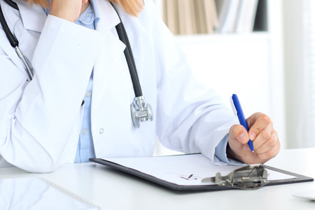 Close up of a female doctor writing a medical prescription, just hands.の写真素材