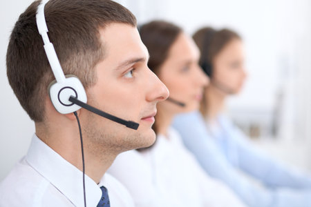 Call center operators. Focus at businessman in headset while consulting customersの写真素材