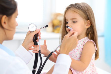 Doctor examining a little girl by stethoscopeの写真素材