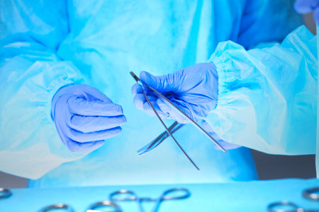 Close-up of of surgeons hands at work in operating theater toned in blueの写真素材