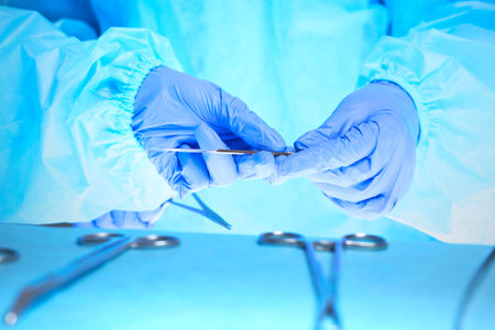 Close-up of of surgeons hands at work in operating theater toned in blueの写真素材
