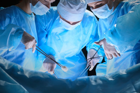 Group of surgeons at work in operating theater toned in blueの写真素材