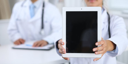 Young female doctor holding touch pad or tablet with copy space. Advertising in medicine.の写真素材