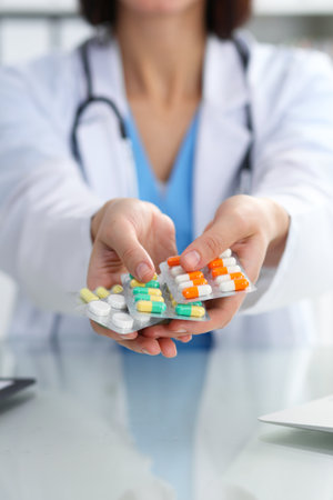 Female doctor hand holding pack of different tablet blisters closeup. Life save service, legal drug store, prescribe medicament, blood pressure, disease healing concept.の写真素材
