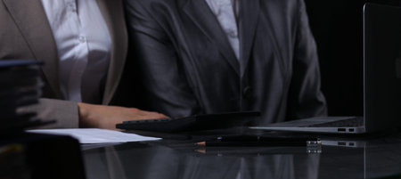 Group of businesspeople or lawyers at meeting. Close-uo of human hands at work. Low key lighting.