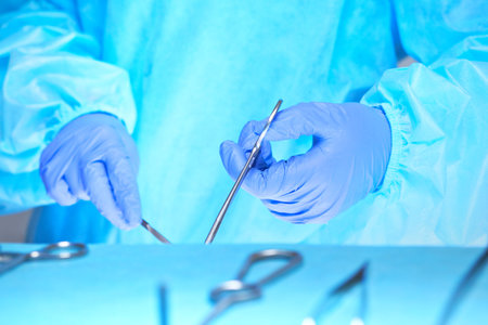 Close-up of of surgeons hands at work in operating theater toned in blue. Medical team performing operationの写真素材