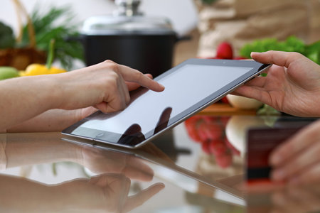 Close-up of human hands pointing into tablet  in the kitchen. Friends having fun while choosing menu...