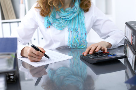 Female bookkeeper or financial inspector  making report, calculating or checking balance. Internal Revenue Service checking financial document. Audit concept.の写真素材