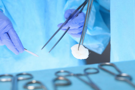 Close-up of of surgeons hands at work in operating theater toned in blue. Medical team performing...
