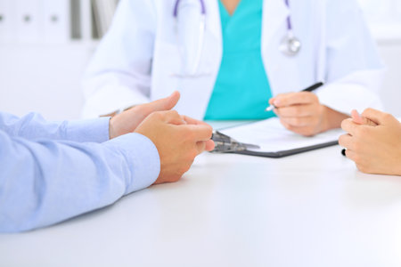 Doctor and patient couple are discussing something, just hands at the table.の写真素材