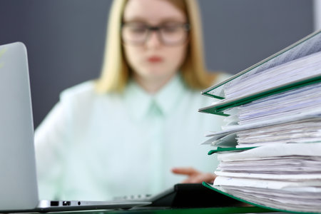 Bookkeeper or financial inspector  making report, calculating or checking balance. Binders with papers closeup. Audit and tax service concept. Green colored image backgroundの写真素材
