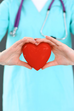 Female doctor with stethoscope holding heart in her arms. Healthcare and cardiology concept in medicineの写真素材