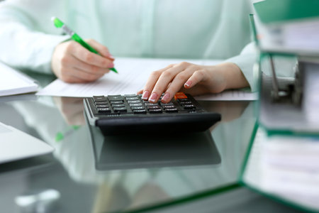 Bookkeeper or financial inspector  making report, calculating or checking balance. Audit and tax service concept. Green colored image backgroundの写真素材