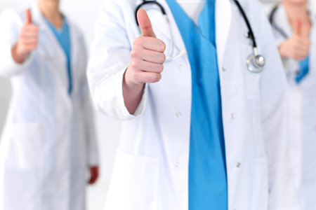 Groupe of medicine doctors show OK sign with thumb up close up. Success and high level service in health care, best treatment and customer loyalty and physical concept. Copy space for advertisementの写真素材