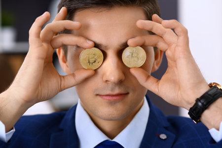 Businessman holding golden bitcoin and smiling. Virtual anonymous money concept, success in digital financeの写真素材