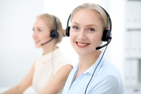 Image of bright call center. Focus on young beautiful woman in a headsetの写真素材