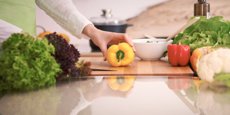 Close Up of human hands cooking vegetable salad in kitchen on the glass table with reflection. Healthy meal, and vegetarian food conceptの写真素材